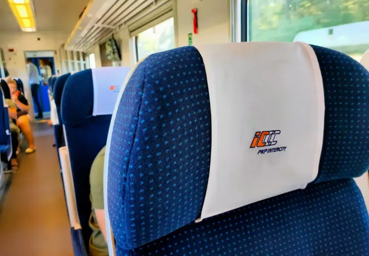 Wnętrze pociągu PKP Intercity. Siedzenia z zagłówkami, na których widnieje logo przewoźnika. Czy bilet PKP z rezerwacją miejsca czy bez – kiedy warto dopłacić?