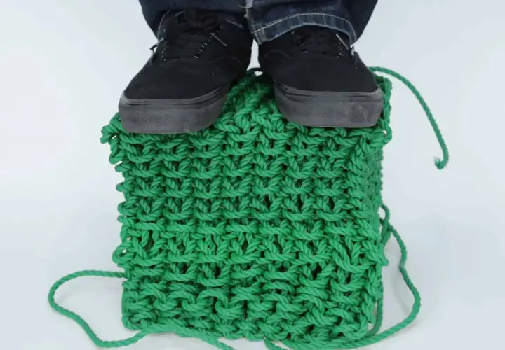 Pieds chaussés sur un cube de tricotage 3D vert vif, démontrant la solidité de la maille.