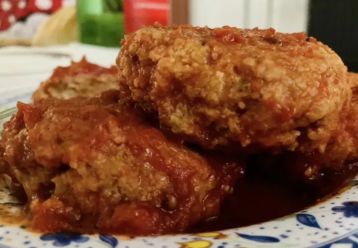 Polpette al sugo fumanti in una padella di ghisa, guarnite con prezzemolo fresco. Un classico confortante.