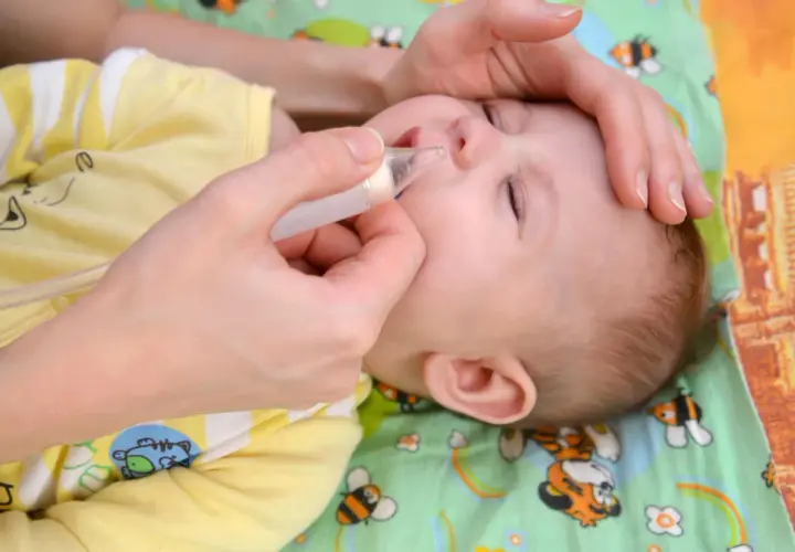 Mani delicate aiutano un neonato di 1 mese con il raffreddore, usando un aspiratore nasale per liberare il piccolo nasino.