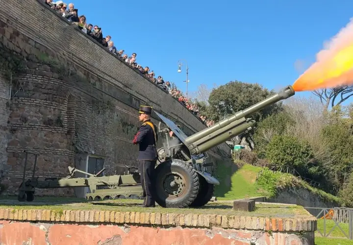Il cannone Gianicolo spara una palla di fumo arancione e gialla. Un soldato in uniforme osserva, mentre una folla guarda dall'alto.