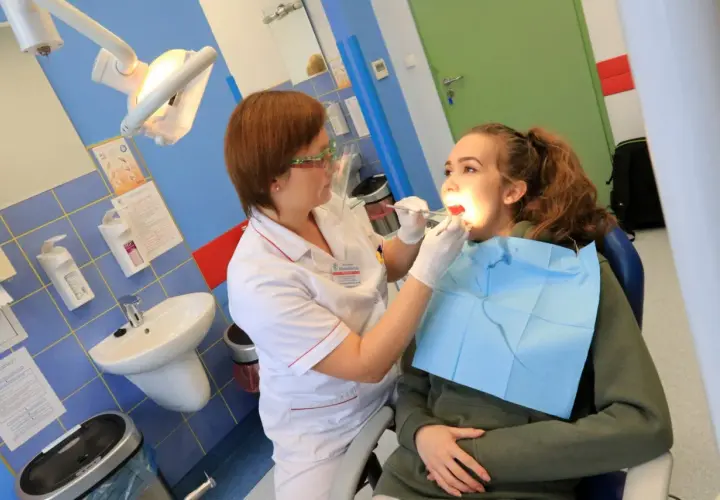 Dentystka bada zęby młodej pacjentki w gabinecie stomatologicznym.