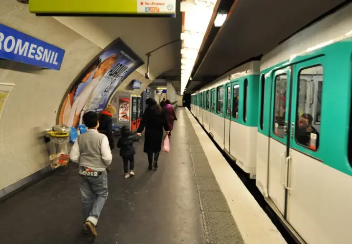 Na stacji Miromesnil w Paryżu widać pociąg metra. Ludzie czekają na peronie, a mapa metra wisi na ścianie.