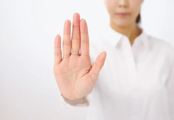 Dłoń uniesiona w geście stop. To symbol asertywności i stawiania granic.