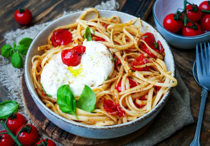 Spaghetti mit Burrata, Kirschtomaten und frischem Basilikum. Cremiger Käse schmilzt auf den Nudeln.