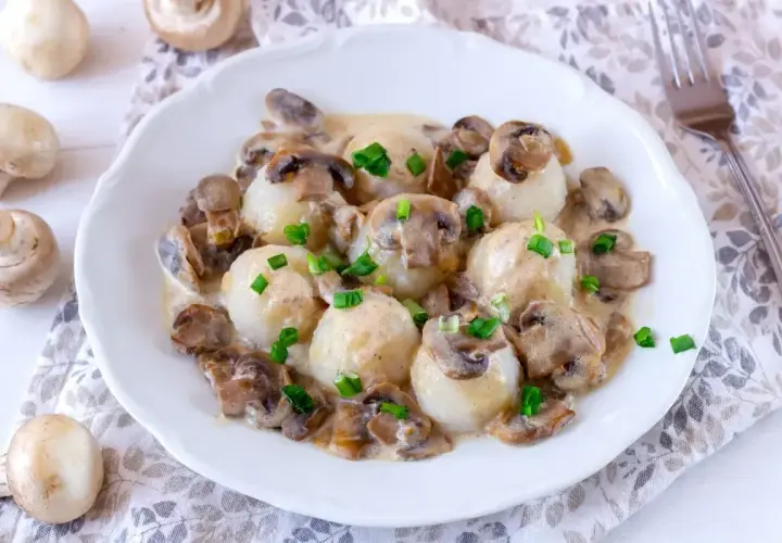 Pyszne kluski ziemniaczane w sosie pieczarkowym. Idealne, gdy zastanawiasz się, jak długo smażyć pieczarki, by były miękkie i aromatyczne.