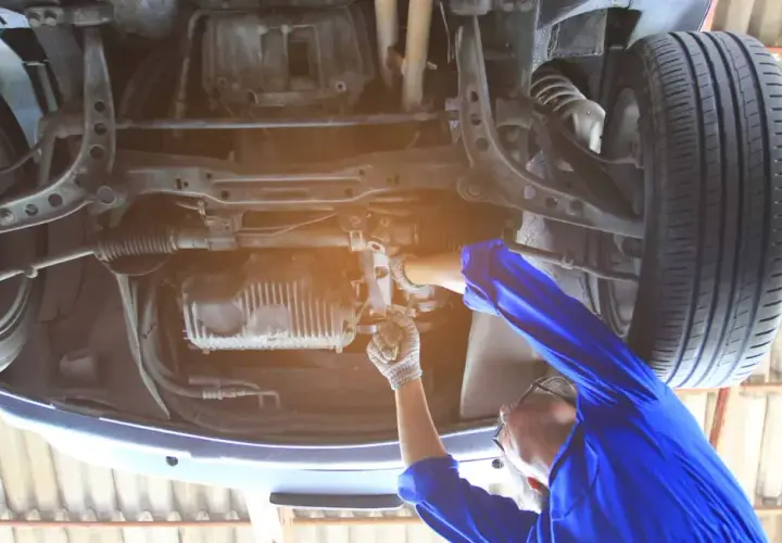 Mechanik pracuje pod samochodem, regulując układ kierowniczy. Dowiedz się, jak skasować luz na maglownicy.