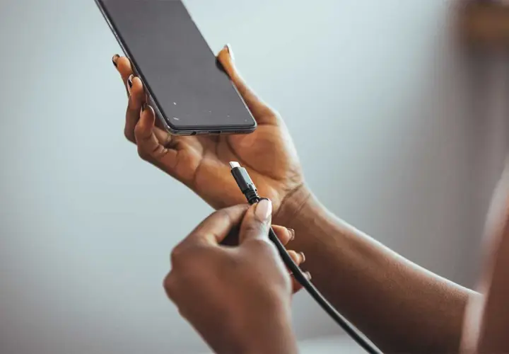 Dłoń z kablem USB przygotowuje się do podłączenia do telefonu, pokazując, jak naładować telefon telefonem.