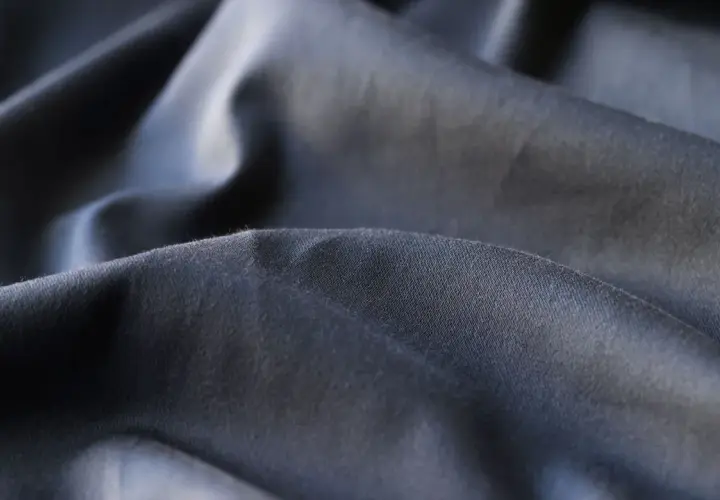Plis du polyester tissu, d'une teinte gris foncé, créant des ombres douces et des reflets subtils.