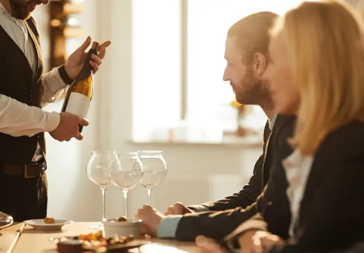 Ein Sommelier präsentiert eine Weinflasche. Die Bedeutung eines Sommeliers liegt in seiner Expertise für Wein und Speisen.