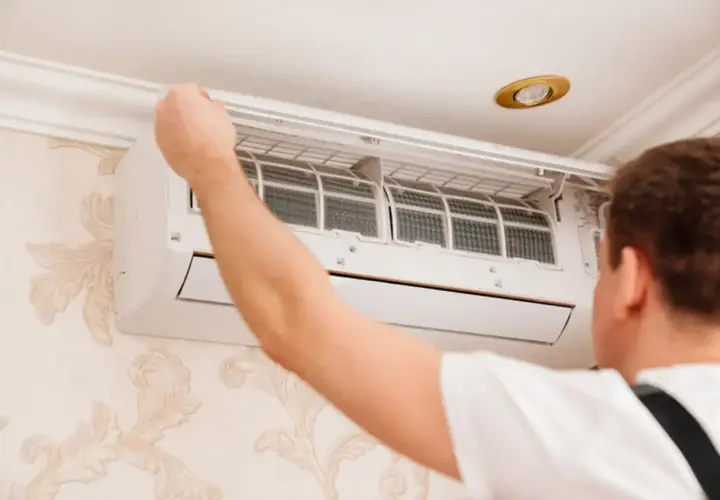 Technik sprawdza filtry klimatyzatora. Czy montaż klimatyzacji wymaga zgłoszenia? Zależy od przepisów.
