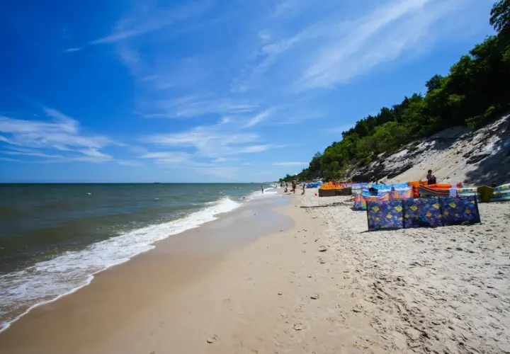 Słoneczna plaża w Chłapowie z kolorowymi parawanami, idealne miejsce na rodzinne wakacje i atrakcje dla dzieci.