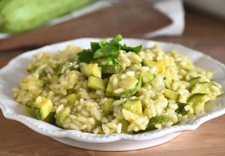 Un cremoso risotto con zucchine, guarnito con prezzemolo fresco. Un piatto estivo che profuma di casa.