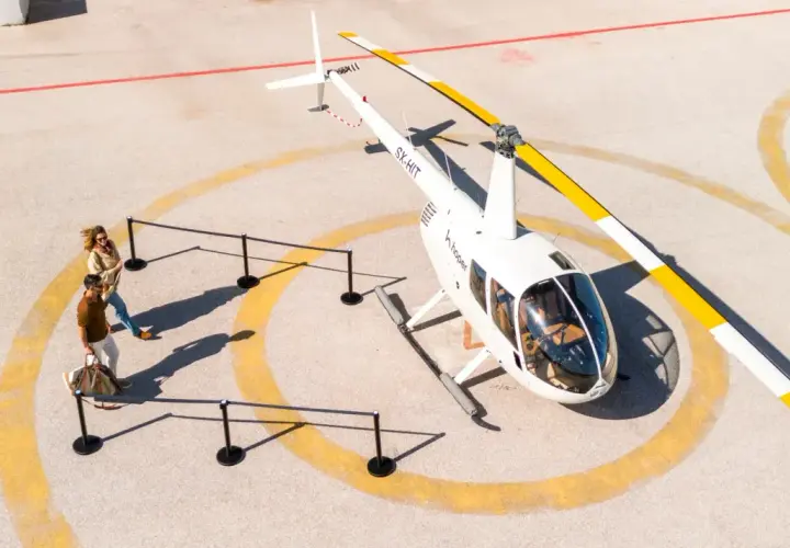 Para zwiedzających zbliża się do helikoptera. Sprawdź hopper ceny biletów na niezapomnianą podróż!