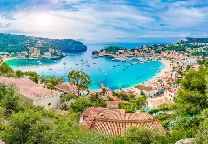 Bahía turquesa con barcos y casas en laderas verdes, un paraíso que evoca **islas secretas** y tranquilidad.