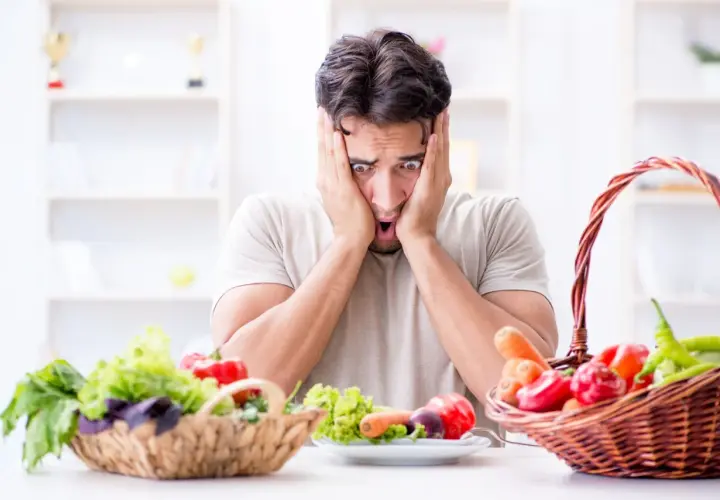 Uomo con espressione terrorizzata davanti a verdure fresche, simbolo di neofobia alimentare adulti.