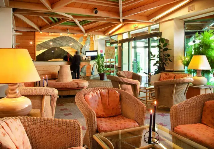 Lobby d'hôtel avec fauteuils en rotin, lampes et réception.