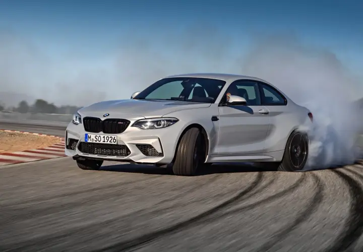Un BMW M2 Competition CV derrapa en una pista, dejando estelas de humo y marcas de neumáticos.