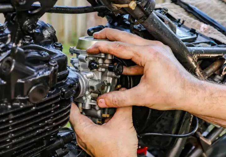 Manos ajustando el ahogador de moto, pieza clave para el arranque en frío.