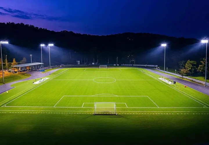 Piłkarskie boisko oświetlone mocnym oświetleniem stadionowym, gotowe na nocny mecz.