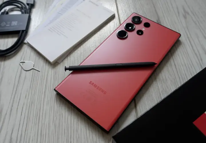 Czerwony Samsung S23 Ultra z rysikiem i akcesoriami. Aparat tego modelu pozwala na robienie niesamowitych zdjęć.