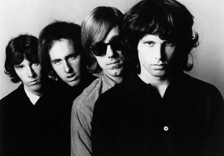 Czterech członków zespołu The Doors, w tym Jim Morrison z przodu, patrzą w obiektyw.