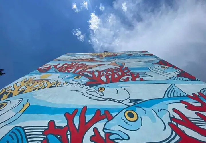 Un'onda di colori subacquei decora un muro a Roma, un'esplosione di vita marina e coralli rossi. Roma street art che porta il mare in città.