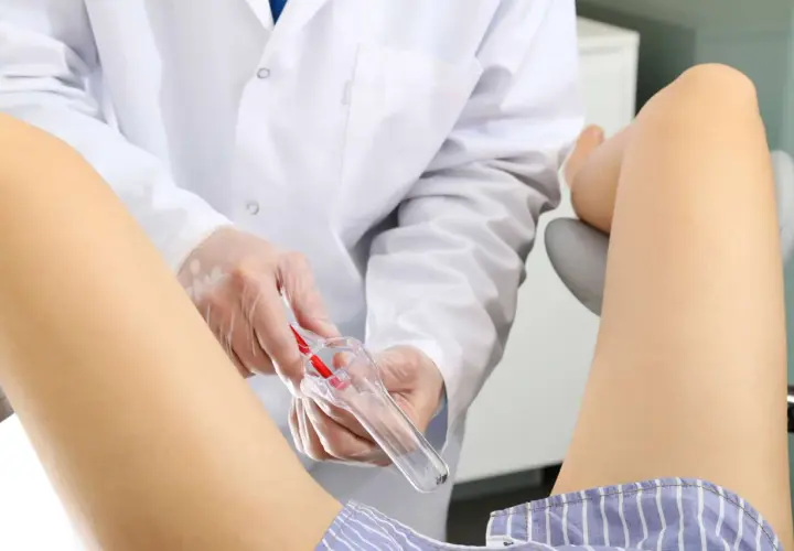 Ginekolog w białym fartuchu przygotowuje wziernik do badania. Dbałość o zdrowie kobiety, nawet w trudnym okresie.