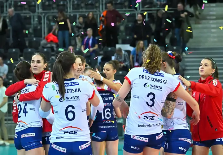 Siatkarki w strojach sportowych przytulają się, obsypane konfetti.