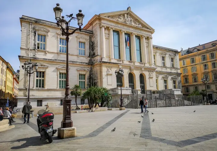 Plac przed Pałacem Sprawiedliwości na Cours Saleya. Skuter, latarnie i gołębie na brukowanym placu.