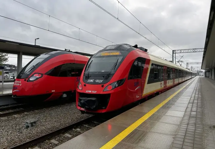 Dwa czerwone pociągi SKM stoją na stacji. Jeden z nich ma na wyświetlaczu informację "SKM Trasa Skrócona", sugerując przebookowanie.