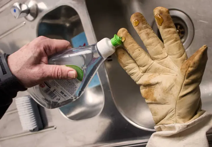 Tropfen Spülmittel auf schmutzige lederhandschuhe, um sie zu waschen.