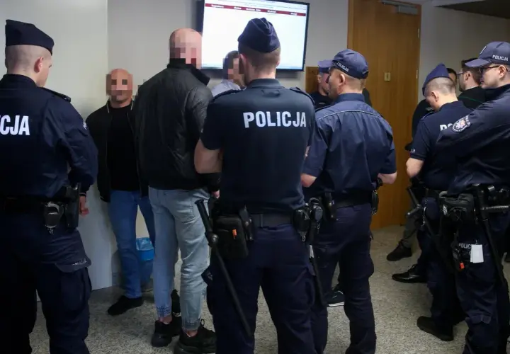 Policjanci otaczają grupę mężczyzn, wśród których mogą być psycho fans. Wszyscy mają zakryte twarze.