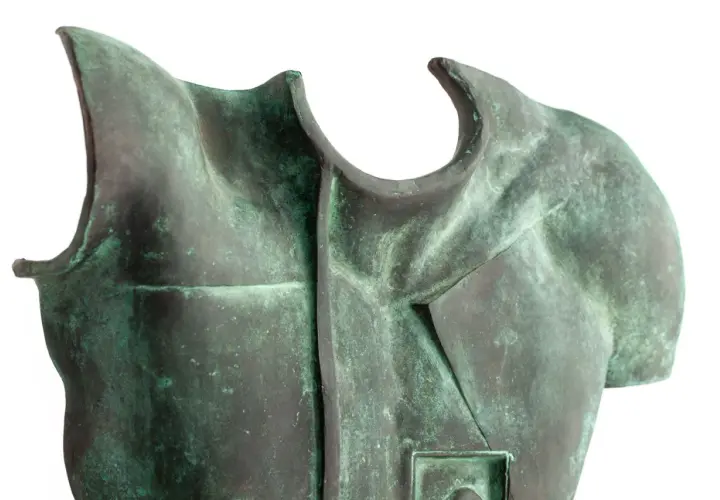Fragment rzeźby z brązu przedstawiający tors z zieloną patyną.