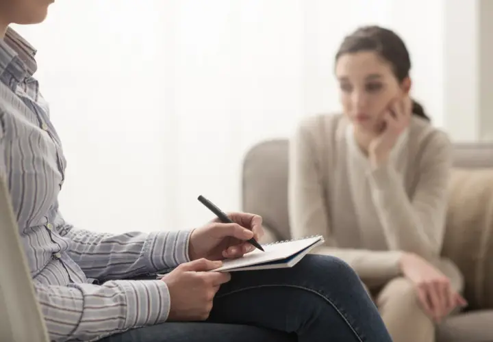 Psycholog notuje podczas sesji. Zastanawiasz się, ile zarabia psycholog? To zależy od wielu czynników, ale warto wiedzieć, że praca ta jest wymagająca i satysfakcjonująca.