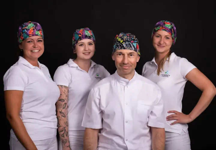 Cztery osoby w białych uniformach i kolorowych czepkach stomatologicznych na czarnym tle.
