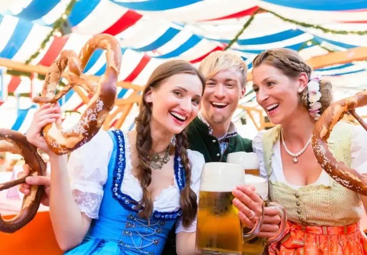 Trois amis joyeux célèbrent à l'Oktoberfest, un lieu festif, avec des bretzels géants et de la bière.