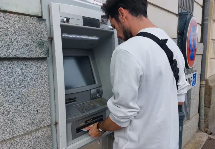 Un homme retire de l'argent à un distributeur automatique. Il suit les étapes pour comment retirer de l'argent.