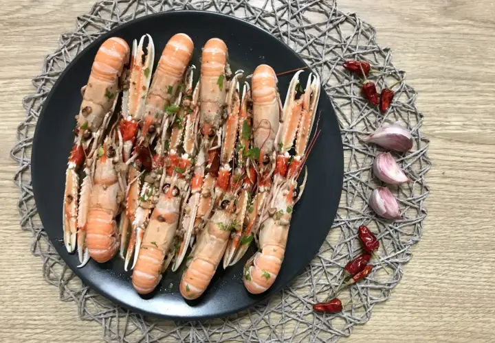 Plato de cigalas al ajillo, con guindillas y ajos.