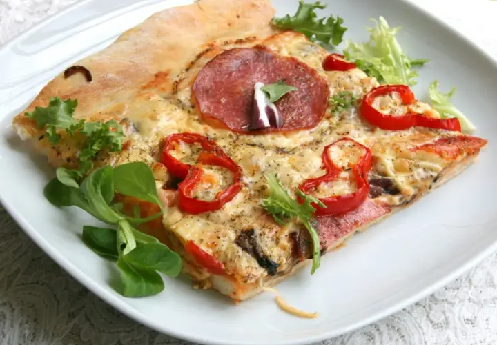 Proste ciasto na pizzę zawsze wychodzi, oto kawałek z salami, papryką i serem, udekorowany świeżą sałatką.