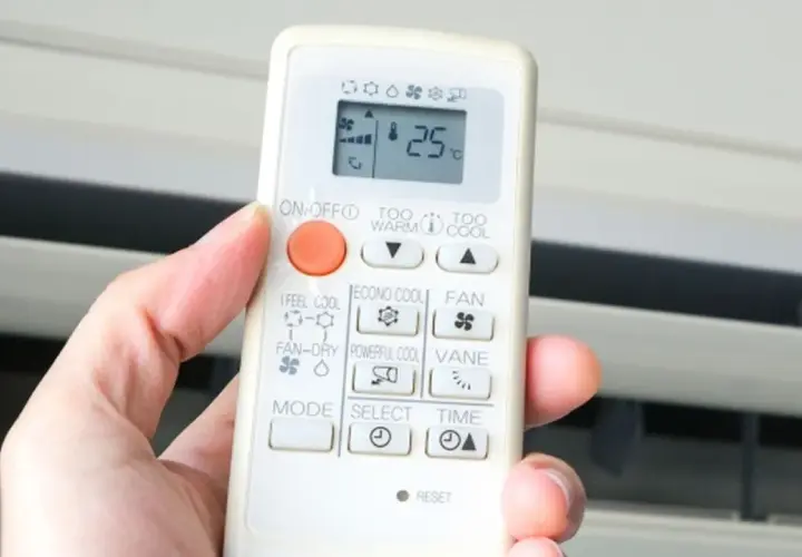 Mano sujetando control remoto de aire acondicionado. El símbolo del triángulo indica la función de enfriamiento.