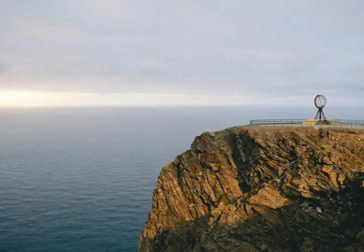 Skała na Nordkapp z globusem i morzem w tle.