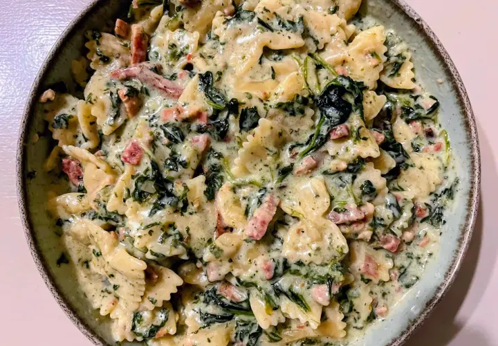 Pyszny makaron farfalle w kremowym sosie ze szpinakiem i kawałkami boczku. Idealny makaron ze szpinakiem i serem na szybki obiad.