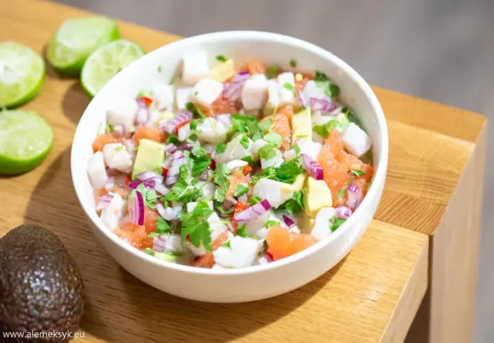 Pyszne ceviche z kawałkami ryby, awokado, grejpfruta, czerwonej cebuli i kolendry, podane w białej misce.