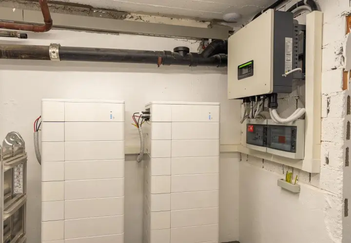 Dwa białe, modułowe systemy **bess** obok siebie, podłączone do falownika i rozdzielnicy elektrycznej.