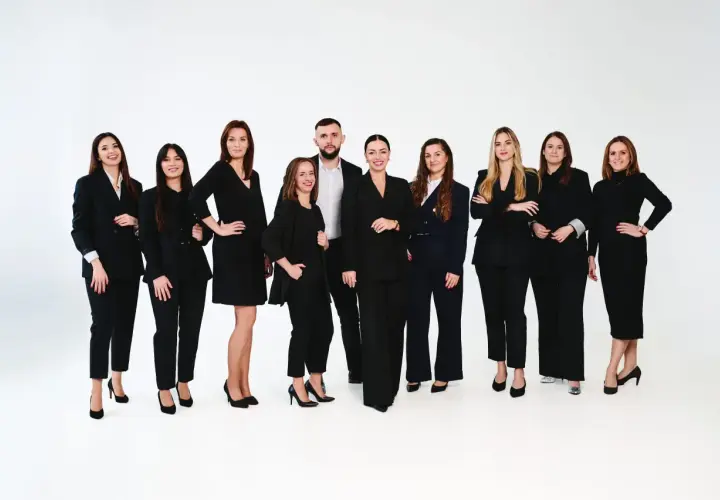 Grupa profesjonalistów w czarnych garniturach na białym tle.