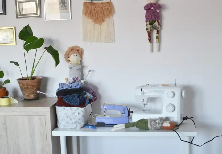 Urocza domowa pracownia krawiecka z maszyną do szycia, zabawkami i materiałami do rękodzieła.
