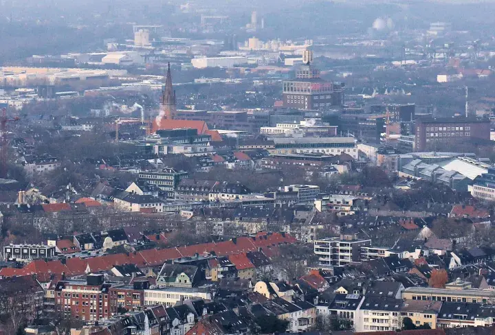 Rozległy krajobraz miejski, gdzie widać charakterystyczne budynki i dachy, tworzy obraz miasta Dortmund.