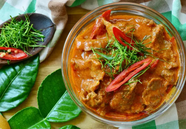 Un délicieux boeuf curry rouge, garni de piments et d'herbes fraîches, prêt à être dégusté.