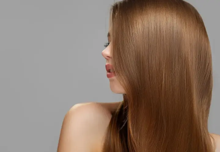 Mujer con cabello largo y liso de tono castaño claro, con reflejos dorados.